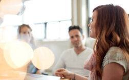 Candid picture of a business team collaborating. Filtered serie with light flares, bokeh  and warm sunny tones.