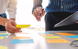 Business people arranging sticky notes commenting and brainstorming on work priorities colleague in a modern co-working space. Business people arranging sticky notes commenting and brainstorming on work priorities colleague in a modern co-working space