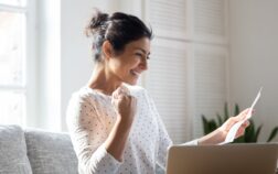 Happy Indian woman reading good news in letter, notification Happy Indian woman reading good news in letter, notification, holding paper, smiling girl rejoicing success, student excited by positive exam results, showing yes gesture, sitting on couch at home