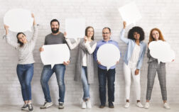 People carryng speech bubble icons at studio People carrying speech bubble icons with free space, standing at white brick wall, ready for your text