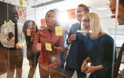 Laughing businesspeople having a brainstorming session in an off Laughing group of diverse businesspeople having a brainstorming session together with sticky notes in an office
