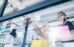 Young creative business people meeting at office. Business people meeting at office and use post it notes to share idea. Brainstorming concept. Sticky note on glass wall.