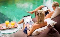 Couple working on computers while relaxing by the pool. Couple working on computers while relaxing by the pool.